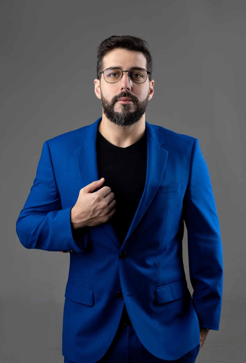 Wilian Bard, de terno azul e óculos, olhando para a câmera